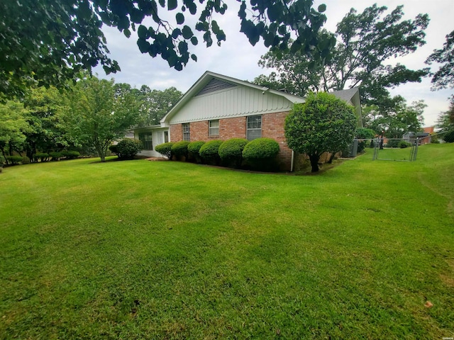 view of side of property with a yard, fence, and brick siding