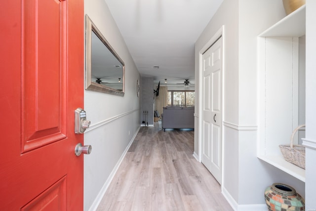 corridor featuring baseboards and light wood finished floors