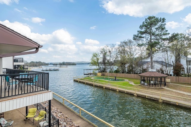 dock area with a gazebo, a water view, and fence