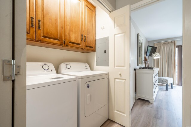 clothes washing area with cabinet space, light wood-style flooring, electric panel, and washer and dryer