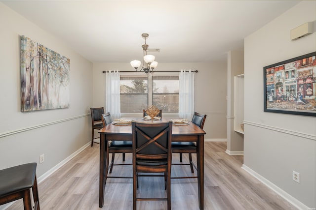 dining area with light wood-type flooring, baseboards, and a notable chandelier