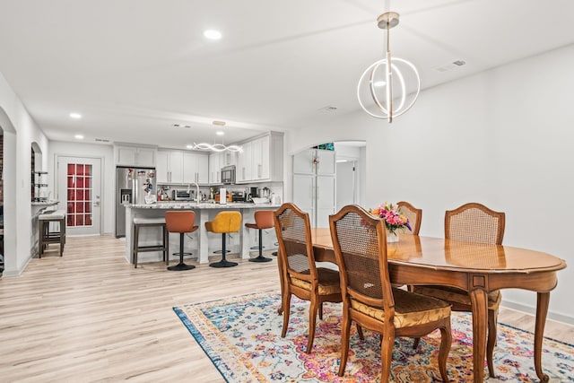 dining room with visible vents, arched walkways, light wood-style flooring, and recessed lighting