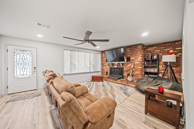 living room with brick wall, wood finished floors, visible vents, and a ceiling fan