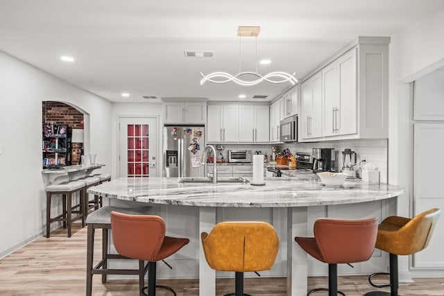 kitchen with light stone counters, a peninsula, a sink, appliances with stainless steel finishes, and backsplash