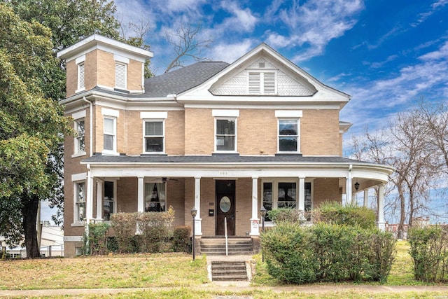 view of front of house with brick siding, a front lawn, and a porch