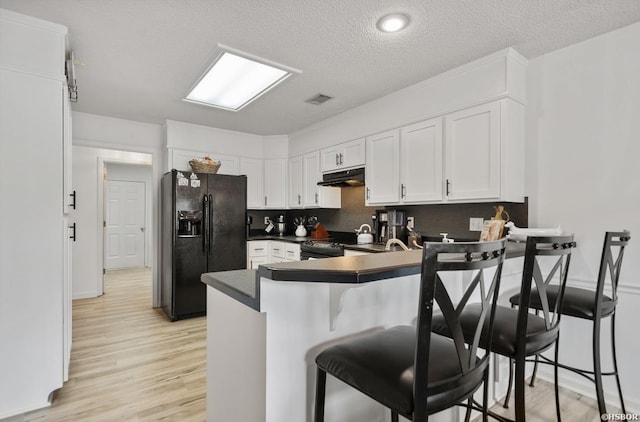200 Cole Pl, Hot Springs, AR 71901 - kitchen with black appliances, under cabinet range hood, a peninsula, white cabinetry, and light wood-style flooring