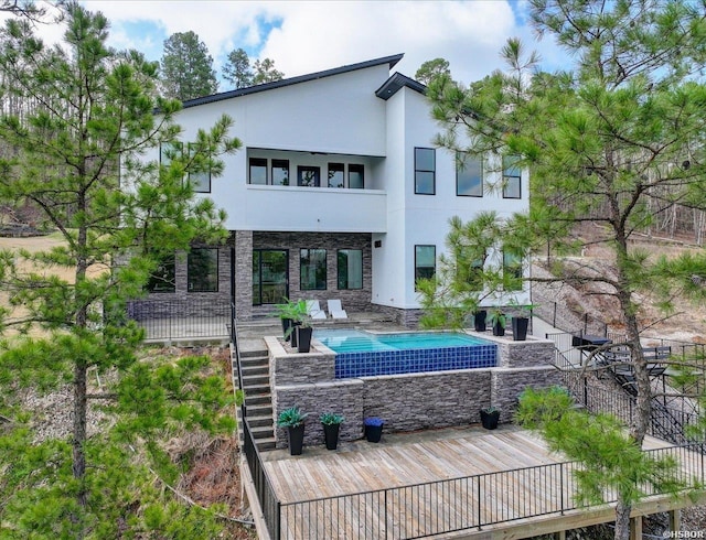 rear view of property featuring stairway, an outdoor pool, stucco siding, stone siding, and a patio area