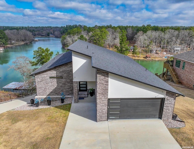 exterior space featuring stone siding, concrete driveway, and a water view