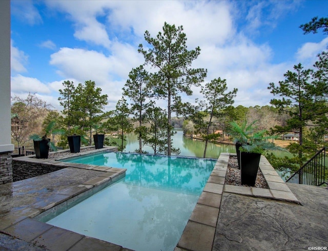 outdoor pool featuring a water view and a patio area