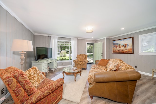 living area featuring wood finished floors, a healthy amount of sunlight, and crown molding