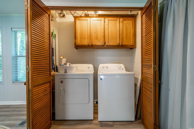 laundry room with wood finished floors, washer and clothes dryer, and cabinet space