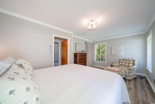 bedroom featuring crown molding, visible vents, wood finished floors, and baseboards