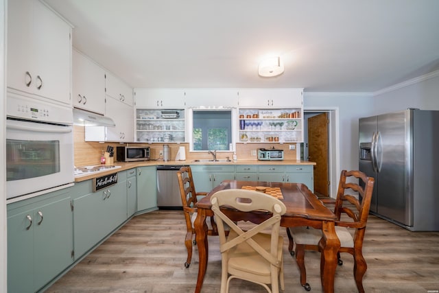 kitchen featuring crown molding, a sink, open shelves, and stainless steel appliances