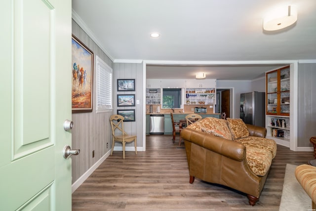 living area featuring light wood-type flooring, recessed lighting, ornamental molding, and baseboards