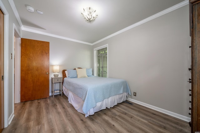 bedroom with crown molding, visible vents, wood finished floors, and baseboards