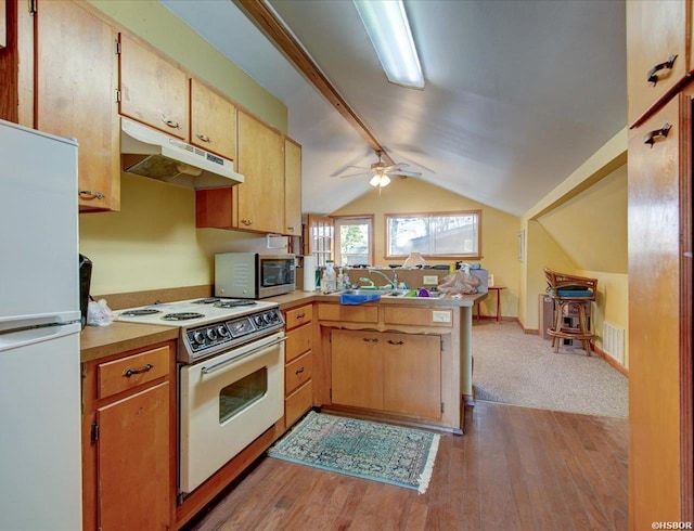 kitchen with light countertops, vaulted ceiling, a peninsula, white appliances, and under cabinet range hood