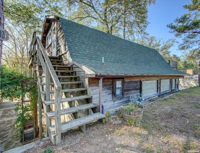 rear view of house featuring roof with shingles and a gambrel roof