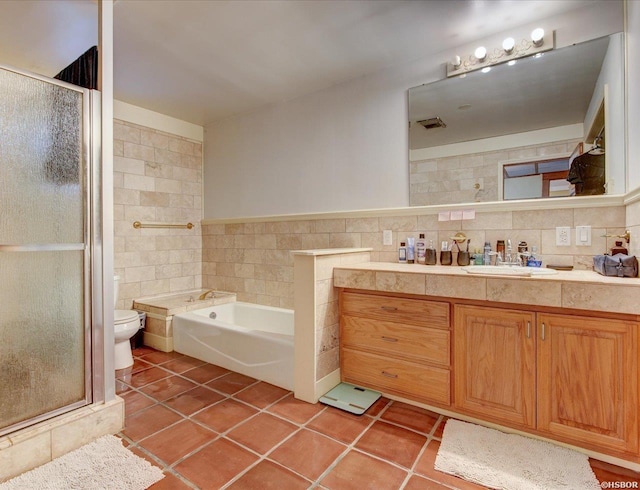 bathroom featuring a garden tub, toilet, vanity, tile walls, and tile patterned floors