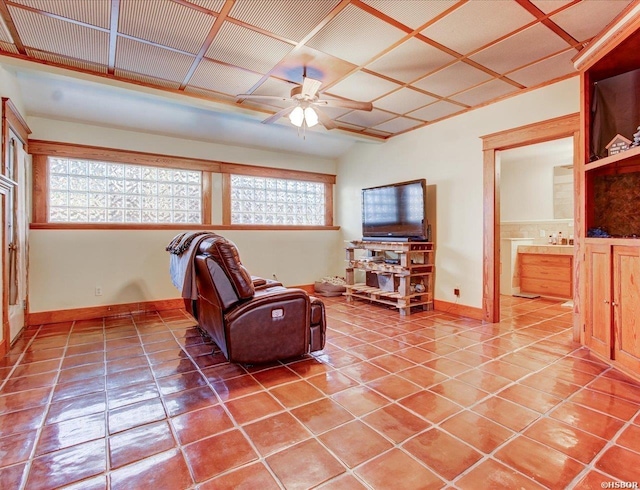 sitting room featuring tile patterned flooring, baseboards, ceiling fan, and a wealth of natural light