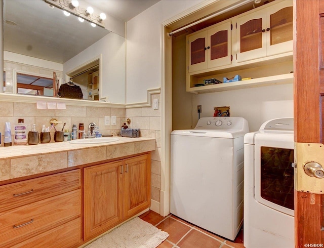 laundry area featuring light tile patterned floors, laundry area, washing machine and dryer, and a sink