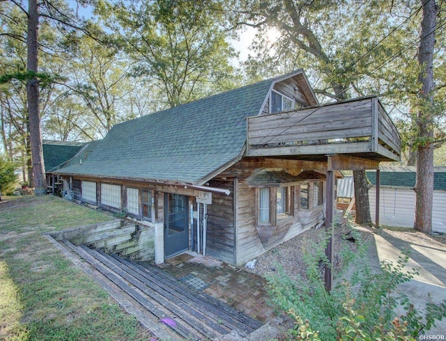 view of front of property featuring roof with shingles, a front lawn, and a gambrel roof