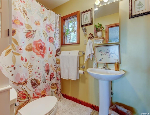 bathroom with a sink, toilet, and baseboards