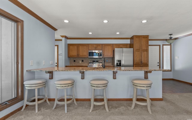 5 Arga Pl, Hot Springs, AR 71909 - kitchen with appliances with stainless steel finishes, brown cabinets, light stone counters, light colored carpet, and crown molding