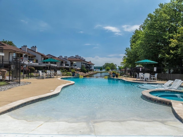 pool with a residential view, fence, a community hot tub, and a patio