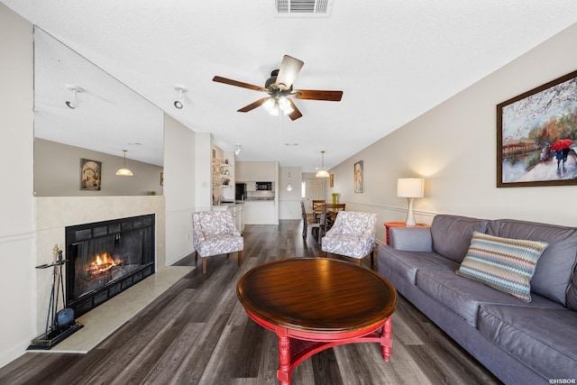 living room featuring visible vents, lofted ceiling, dark wood-style floors, ceiling fan, and a fireplace