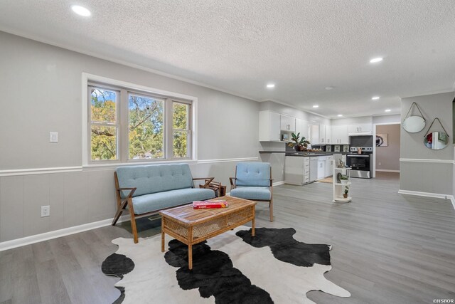 living area featuring light wood-type flooring, wainscoting, a textured ceiling, and recessed lighting