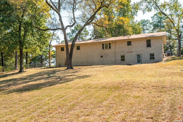 back of property featuring a yard, brick siding, and fence