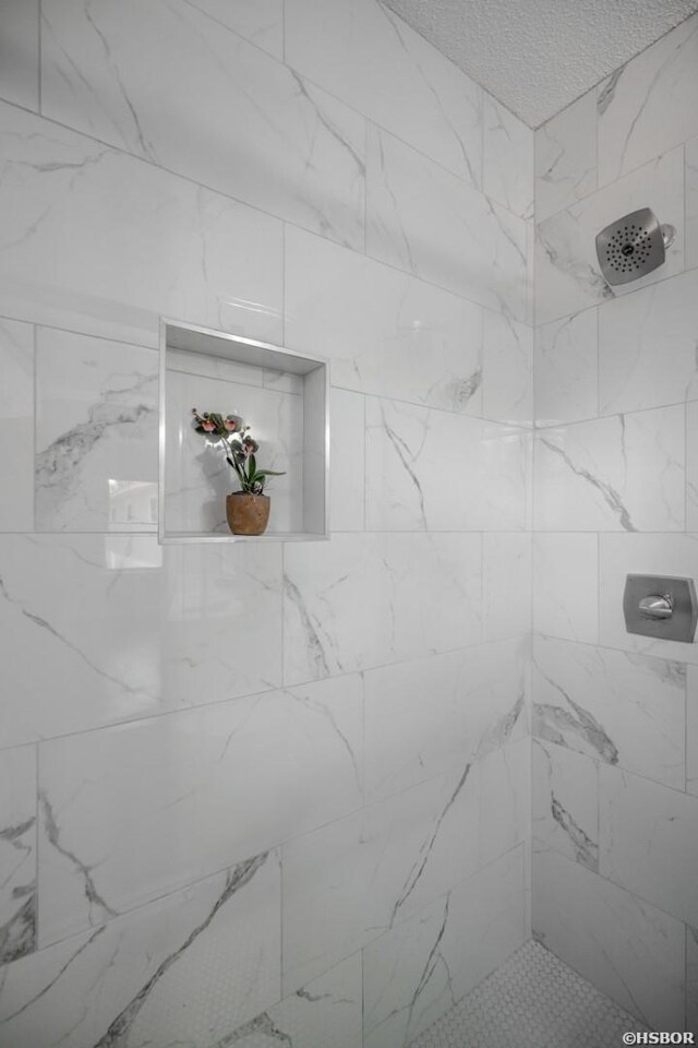 bathroom with a tile shower and a textured ceiling