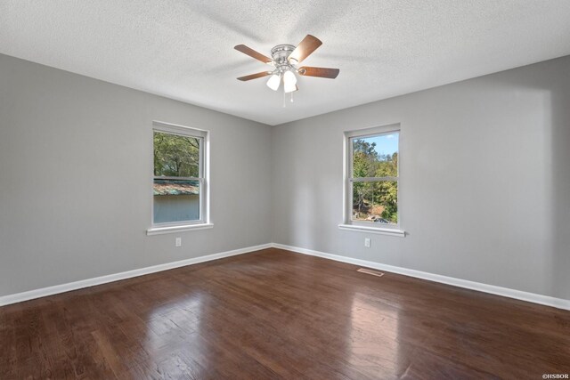 unfurnished room with ceiling fan, a textured ceiling, visible vents, baseboards, and dark wood-style floors