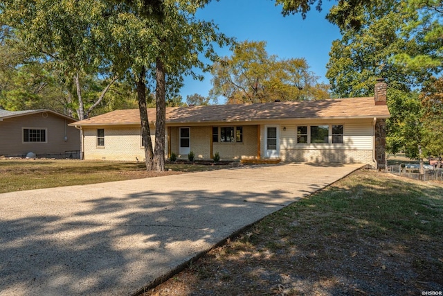 ranch-style house featuring a chimney, a front lawn, and brick siding