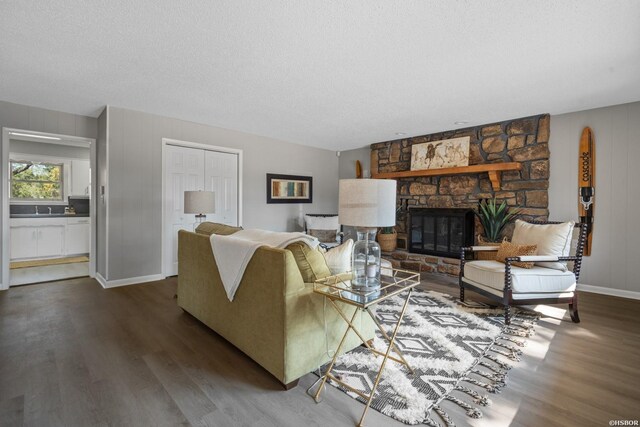 living area featuring a fireplace, baseboards, dark wood finished floors, and a textured ceiling