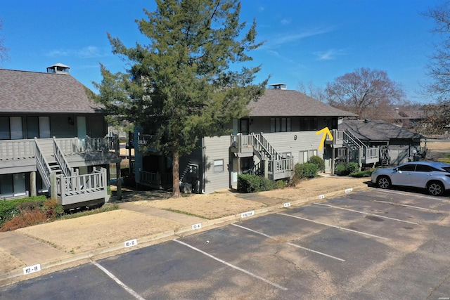 exterior space with uncovered parking, a residential view, a shingled roof, and stairs