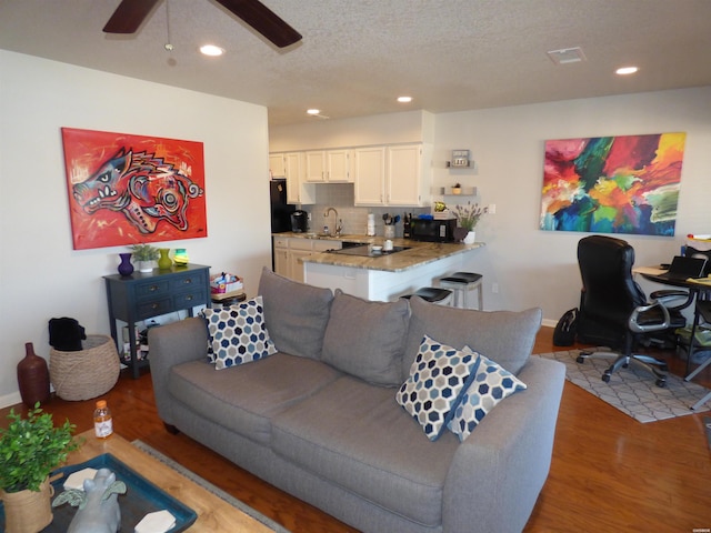 living room with light wood finished floors, recessed lighting, visible vents, a ceiling fan, and a textured ceiling