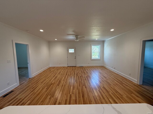 interior space featuring ornamental molding, light wood-style flooring, and baseboards