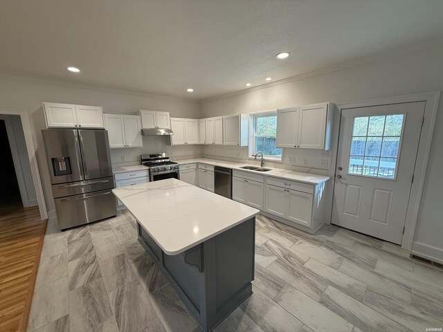 kitchen featuring a sink, white cabinetry, appliances with stainless steel finishes, a center island, and crown molding