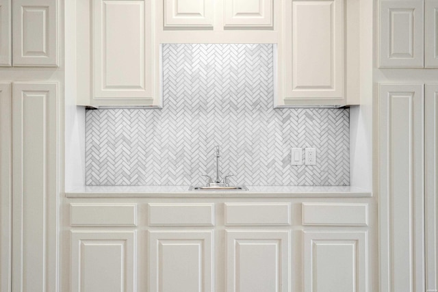 kitchen featuring a sink, light countertops, decorative backsplash, and white cabinetry