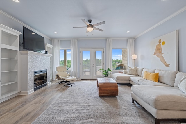 living room featuring a ceiling fan, wood finished floors, a tile fireplace, ornamental molding, and recessed lighting