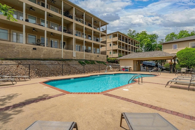 community pool featuring fence, a patio, and ceiling fan