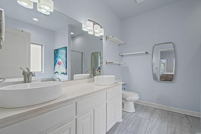 full bathroom featuring double vanity, toilet, baseboards, and a sink