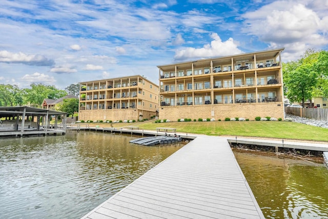 view of dock with a lawn, a water view, and fence