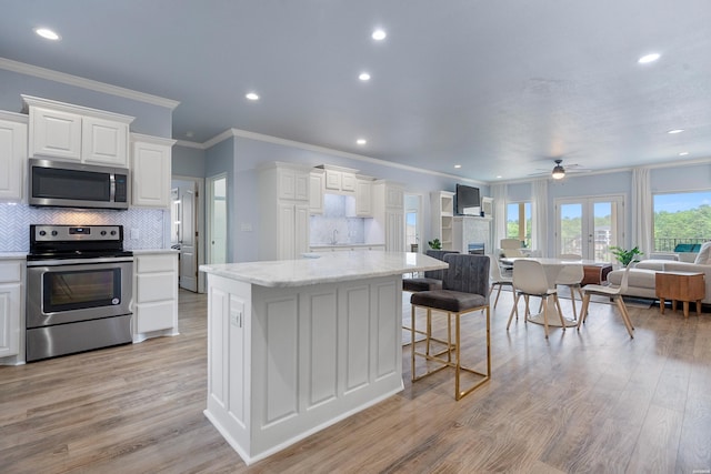 kitchen with open floor plan, appliances with stainless steel finishes, ornamental molding, and tasteful backsplash