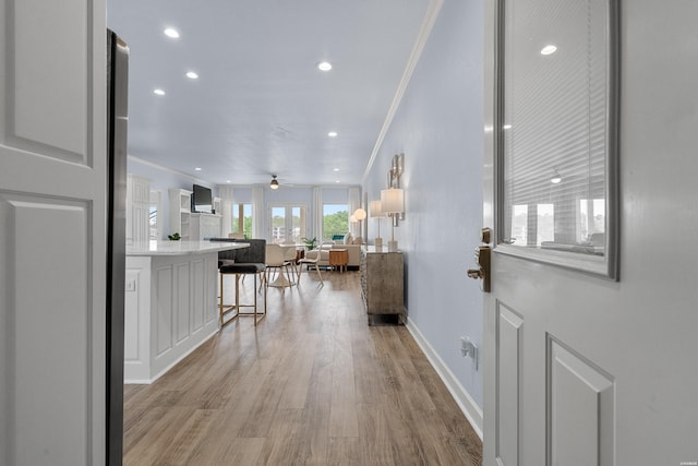 corridor with recessed lighting, baseboards, ornamental molding, and light wood-style floors