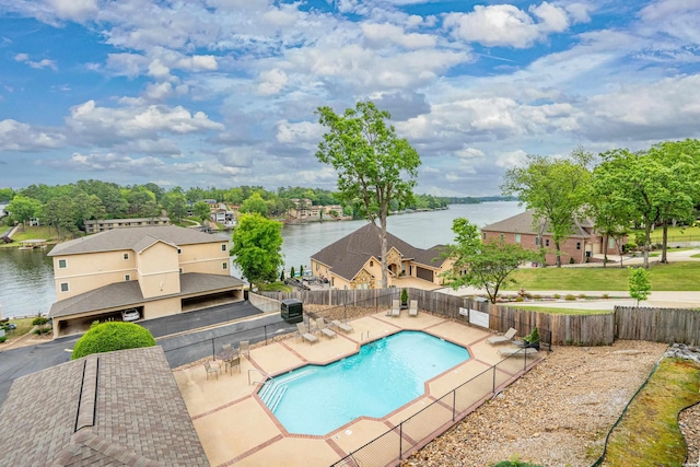 community pool featuring a water view, fence, and a patio area