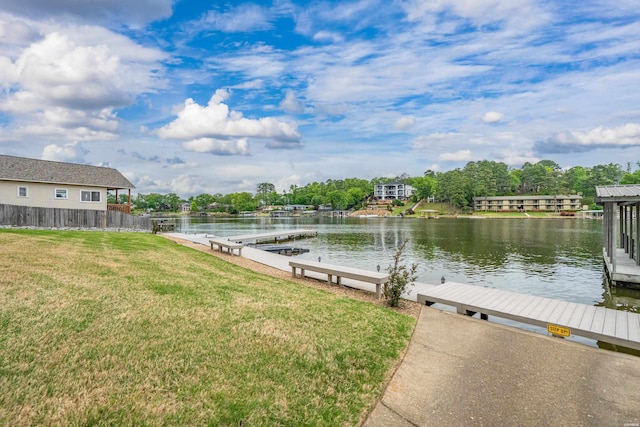 dock area with fence, a water view, and a yard