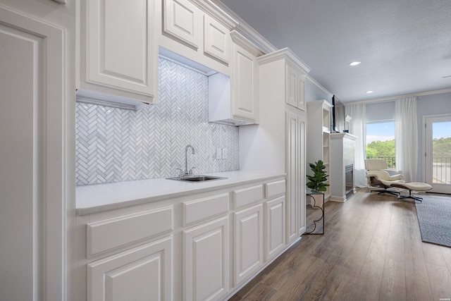 kitchen with a sink, light countertops, white cabinetry, decorative backsplash, and dark wood-type flooring
