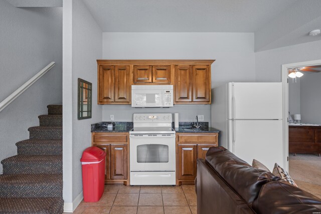 kitchen featuring white appliances, light tile patterned floors, brown cabinetry, dark countertops, and open floor plan